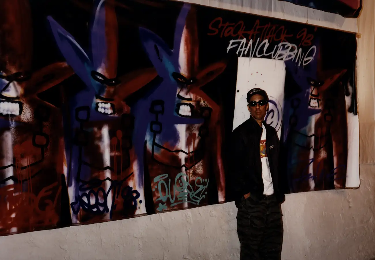 Artist posing with a mural