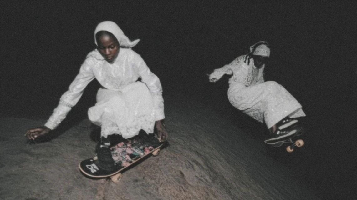 Two figures skateboarding at night, black and white