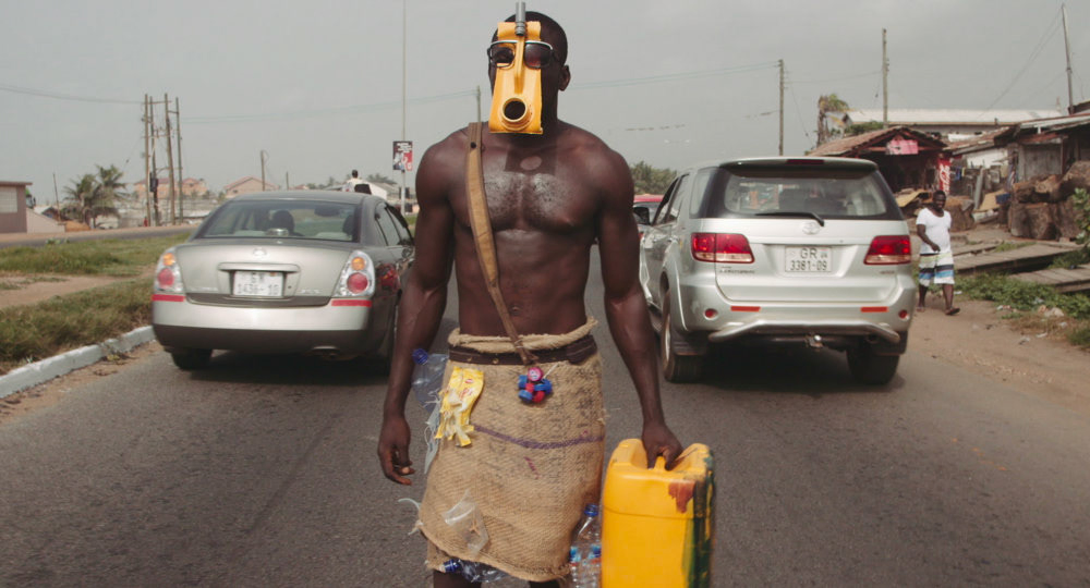 Masked performer walking a city street