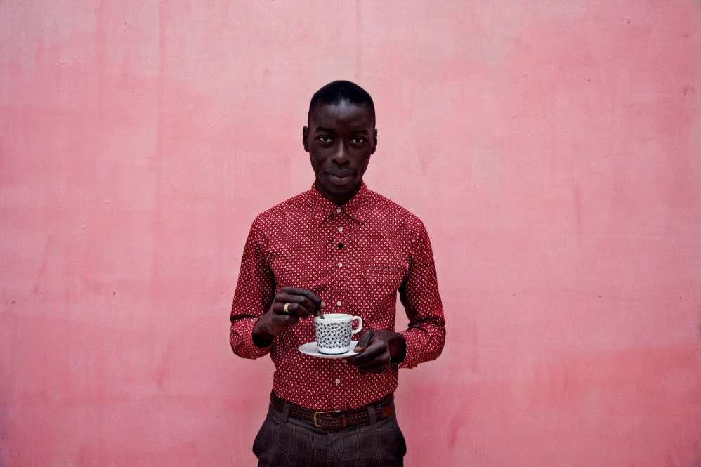 Portrait with espresso cup against a pink wall